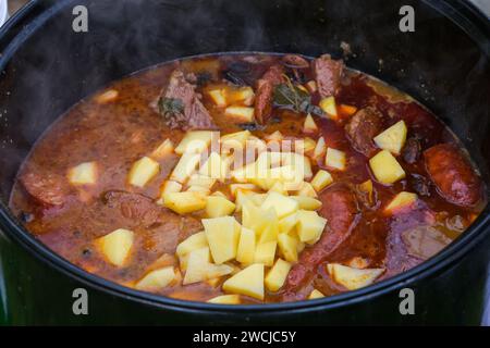 Bohnengulasch, gekocht über offenem Feuer in einem großen Kessel unter freiem Himmel. Stockfoto