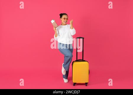 Fröhliche junge asiatische Reisende, die einen Pass mit Tickets hält und Erfolge feiert Stockfoto