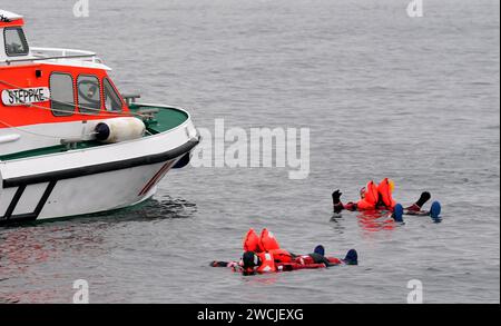 16. Januar 2024, Schleswig-Holstein, Laboe: Björn beide (Front) und Axel Stosberg, Mitglieder der norddeutschen Band Santiano und Ehrenbotschafter der Seerettler, schwimmen während einer Übung in Überlebensanzügen in der Ostsee und werden von dem Seerettungsschiff Steppke gerettet. Im vergangenen Jahr retteten deutsche Seeretter des Deutschen Seerechtsdienstes (DGzRS) bei 1938 Einsätzen in Nord- und Ostsee insgesamt 3.532 Menschen. Sie mussten allein 103 Menschen aus Seenot retten, wie die DGzRS am Dienstag mitteilte. (An die dpa'Seenotretter helfen mehr als 3.500 Menschen Stockfoto