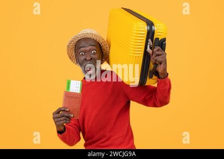 Verblüffter Afroamerikaner mit Strohhut und rotem Pullover, der einen Pass hält Stockfoto