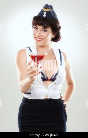 Porträt, Stewardess und glückliche Frau mit Alkohol zu trinken im Studio isoliert auf weißem Hintergrund. Gesicht, Martini Cocktail Glas und Luft Hostess mit Stockfoto