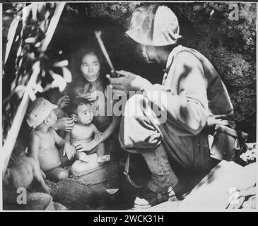 Ein Mitglied einer Marinepatrouille auf Saipan fand diese Familie Japans in einer Höhle am Hügel. Die Mutter, vier Kinder und Stockfoto