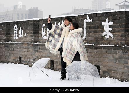 XI'an, chinesische Provinz Shaanxi. Januar 2024. Touristen machen am 16. Januar 2024 ein Selfie auf der schneebedeckten alten Stadtmauer in Xi'an, nordwestchinesischer Provinz Shaanxi. Quelle: Zou Jingyi/Xinhua/Alamy Live News Stockfoto