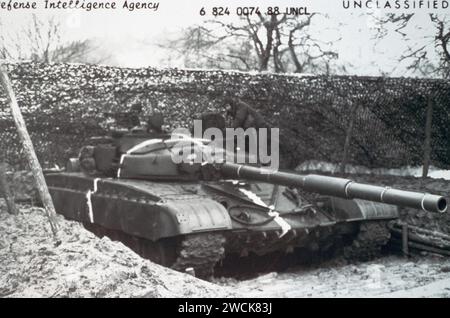 Eine rechte Vorderansicht eines sowjetischen Kampfpanzers T74 in einer eingegrabenen und getarnten Position. Die angeschweißten Panzerplatten auf dem Revolverdach, die die späteren T-74-Modelle von früheren T-74- und T-72-Modellen unterscheiden, sind deutlich zu sehen. Stockfoto
