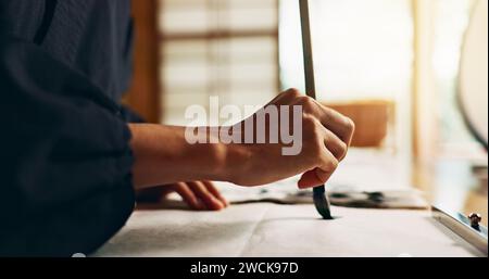 Hände, Pinsel zum Schreiben und alte Schrift für Kunst, Kalligraphie und Nahaufnahme mit Alphabet. Japanisch, Kreativität und Vintage-Werkzeuge, Pinsel und Stockfoto