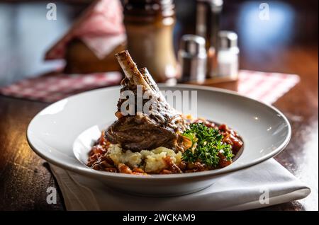 Lammkalb auf Kartoffelpüree und Backsoße konfit. Gebratene Hammelkeule mit Kartoffeln auf einem Teller in einem Restaurant. Stockfoto