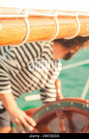 Junger Mann, der das Lenkrad des Schiffes hält und nach unten blickt Stockfoto