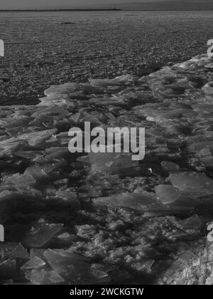 Schwarz-weiße Winterlandschaft mit gefrorenem Eismeer und Leuchtturm auf einem Hintergrund Mangalsala riga 09.01.2024 Stockfoto