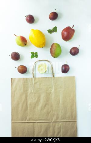 Gesunde Nahrung in einem Kraftpapierbeutel. Zero Waste-Konzept, wiederverwendbares Öko-Pack. Mischung aus verschiedenen Früchten auf weißem Hintergrund, Einkaufspackung, Draufsicht, Stockfoto