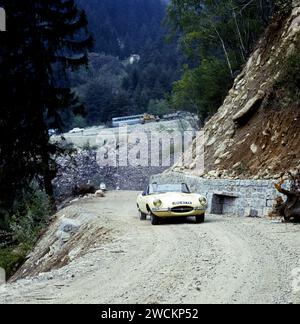 Primrose Yellow Jaguar E-TYPE, Cabriolet, Fahrt auf einer italienischen Bergstraße, mit Bus und anderen Verkehr in der Entfernung im Jahr 1967 Stockfoto