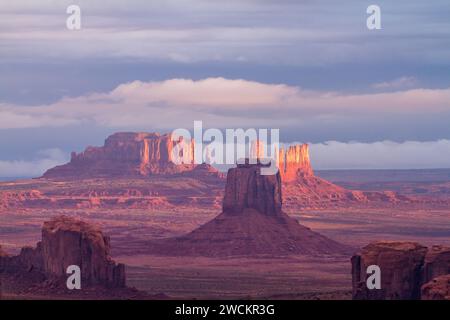 Sonnenaufgang im Monument Valley Navajo Tribal Park in Arizona mit dem East Mitten im Zentrum und den Utah Monuments dahinter. Blick von Hunt's Mesa. Stockfoto