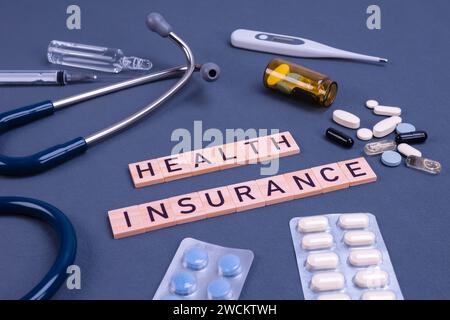 Krankenversicherungstext mit Stethoskop und Pillen auf dem Tisch. Krankenversicherung, Gesundheitsrisiko, Bezahlung für das Gesundheitskonzept. Stockfoto