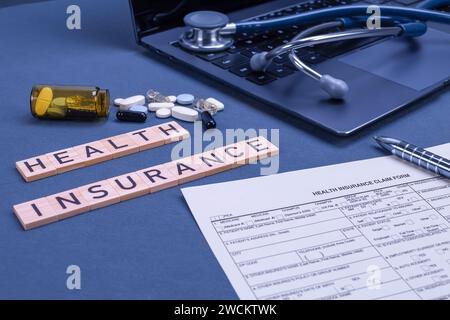 Krankenversicherungsformular Anspruch mit Laptop, Stethoskop und Pillen auf dem Tisch. Krankenversicherung, Gesundheitsrisiko, Bezahlung für das Gesundheitskonzept. Stockfoto