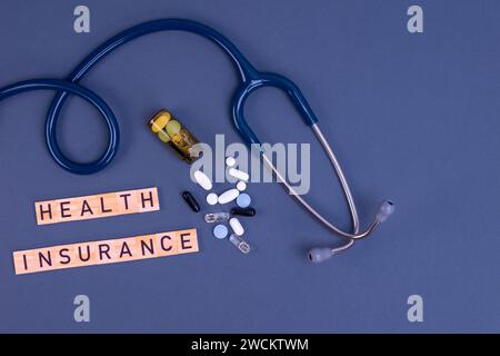 Krankenversicherungstext mit Stethoskop und Pillen auf dem Tisch. Krankenversicherung, Gesundheitsrisiko, Bezahlung für das Gesundheitskonzept. Stockfoto