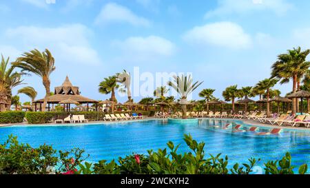 Boa Vista, Kap verde - 22. März 2018: Ein sonniger Tag in einem Hotelpool von Boa Vista mit Palmen, Sonnenschirmen und einer lebhaften tropischen Bar. Stockfoto