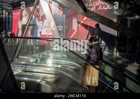 Stadtarbeiter und Käufer in einer urbanen Landschaft mit Reflexionen und Diagonalen an den Rolltreppen in der City of London, dem Finanzviertel der Hauptstadt, am 16. Januar 2024 in London, England. Stockfoto