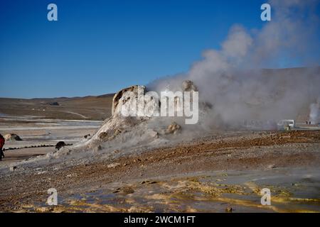 Dampf steigt aus dem Boden, mit Hügeln und blauem Himmel dahinter, in Geysers Del Tatio, Antofagasta, Chile. Stockfoto