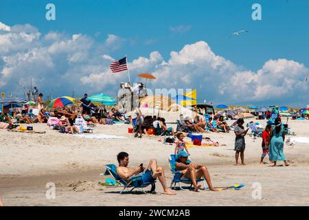 Babylon, New York, USA - 24. Juli 2021: Eine harmonische Zusammenkunft von Menschen findet Trost und Freude, auf den warmen Körnern eines Sandstrandes, der in Flammen steht Stockfoto