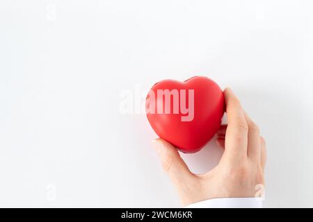 Weibliche Ärztin, die das rote Herz in der Hand hält, isoliert auf weißem Hintergrund. Draufsicht. Kopierbereich. Organspende, Gesundheitswesen, Liebe und medizinische Unterstützung. Stockfoto