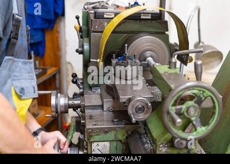 Ein Arbeiter, der in einer Werkstatt an einer alten grünen Drehmaschine arbeitet Stockfoto