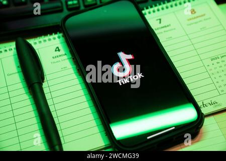 Tik Tok Anwendung auf dem Bildschirm des Apple iPhone 14 Pro Max Smartphones auf der linken Hintergrundtabelle. Büroumgebung. Budapest, Ungarn. Nove Stockfoto