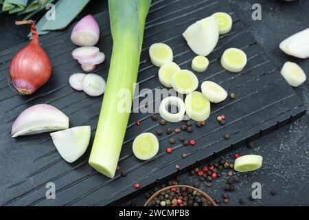 Brett mit verschiedenen Zwiebelsorten auf grunge schwarzem Hintergrund Stockfoto