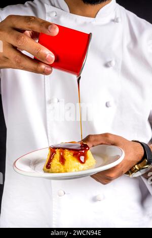 Der Koch gießt süßen Sirup über Karamellpudding. Stockfoto