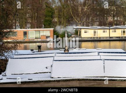 Solarpaneele auf niederländischem Hausboot, das im Winter mit Schnee bedeckt ist Stockfoto