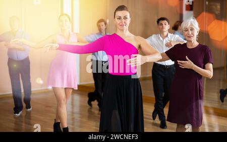 Frau, die langsame Foxtrottbewegungen während des Tanzkurses übt Stockfoto