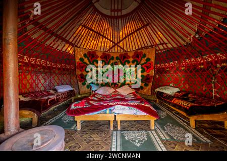 Traditionelle kirgisische Jurte für Übernachtungen für Touristen, mit vier Betten und Teppichen, Region Naryn, Kirgisistan Stockfoto