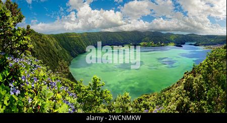 Atemberaubender Panoramablick auf den Kratersee Lagoa Azul, umgeben von steilen Felswänden unter klarem Himmel, runder Kraterwanderweg, Caldeira Stockfoto