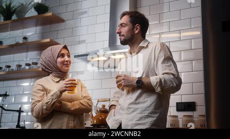 Ein verheiratetes Paar trinkt Orangensaft und hat sich morgens in der Küche unterhalten Stockfoto
