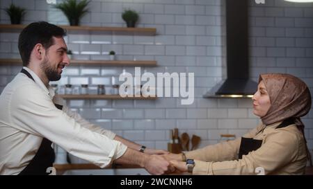 Glückliches verheiratetes Paar mit Kochschürzen und Spaß beim Tanzen während des gemeinsamen Essens, während es Zeit in der modernen Küche verbringt Stockfoto