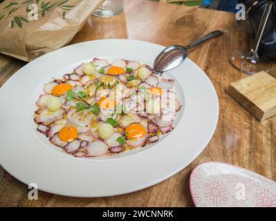 Kraken-Salat in Scheiben mit Lammsalat und Wachteleier. Hintergrund des Tischrestaurants Stockfoto