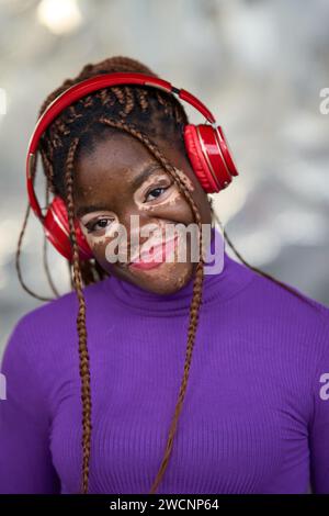 Ruhige Frau in Lila mit roten Kopfhörern Stockfoto