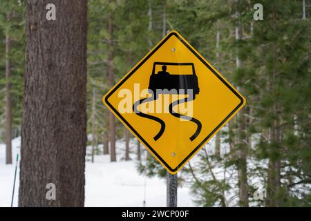 Slipper When Wet Wet Road Schild mit verschneiten Winterkulissen Stockfoto