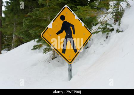 Fußgängerschild im tiefen Schnee entlang der Bergstraße in den Bergen der Sierra Nevada. Stockfoto