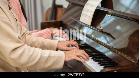 Junge Frau, die Klavierlehrerin für Seniorenlehrerin ist Stockfoto