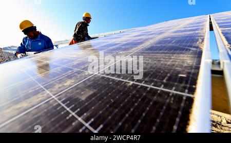 ZHANGYE, CHINA – 16. JANUAR 2024 – Bauherren arbeiten an der Installation von Photovoltaik-Paneelen auf der Baustelle einer 100.000 kw Photovoltaik-Stromerzeugung Stockfoto