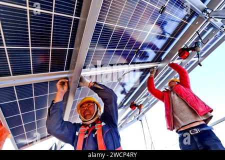 ZHANGYE, CHINA – 16. JANUAR 2024 – Bauherren arbeiten an der Installation von Photovoltaik-Paneelen auf der Baustelle einer 100.000 kw Photovoltaik-Stromerzeugung Stockfoto