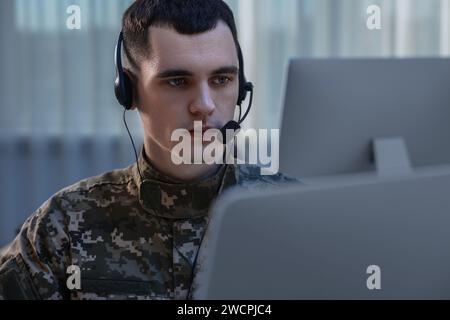 Militärdienst. Junger Soldat in Kopfhörern, der im Büro arbeitet Stockfoto