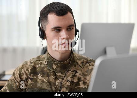 Militärdienst. Junger Soldat in Kopfhörern, der im Büro arbeitet Stockfoto