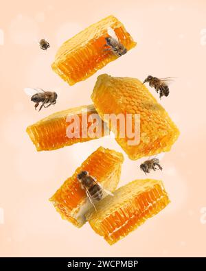 Wabenstücke in der Luft und Bienen fliegen auf beigefarbenem Hintergrund, Bokeh-Effekt Stockfoto