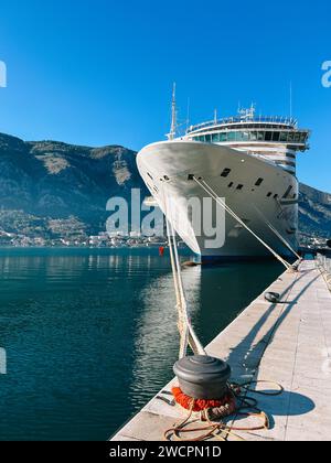 Kotor, Montenegro - 25. dezember 2022: Ein großes Schiff wird vor dem Hintergrund der Berge an den Schiffspollern vor der Anlegestelle vertäut Stockfoto