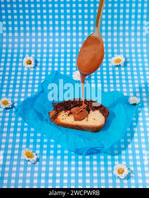 Person, die köstliches Stück Kuchen mit argentinischem Dulce de Leche auf Einem blau-weißen Hintergrund garniert Stockfoto
