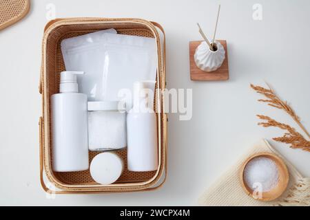 Ein Bambuskorb mit Flaschen ohne Marke, Gesichtsmaske und einem Glas Peeling darin. Draufsicht. Hautpflege, Beauty- und Spa-Angebot Stockfoto