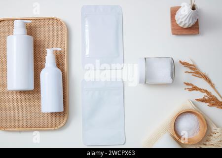 Leere Etiketten für Gesichtsmasken, weiße Flaschen und ein transparentes Glas mit Peeling sind auf weißem Hintergrund dekoriert. Hautpflege-Mockup-Konzept Stockfoto