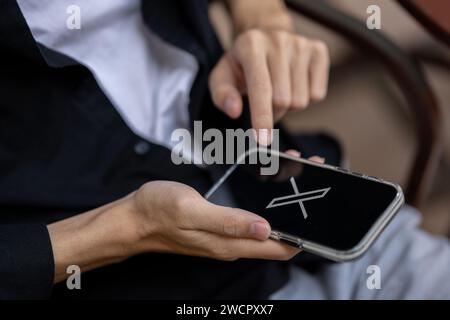 Chiang mai, Thailand - 16. Januar 2024: Ein Mann, der die X-Anwendung auf seinem iPhone verwendet, während er draußen sitzt. X oder neues Twitter-Logo auf einem iPhone-Bildschirm. clo Stockfoto