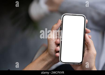 Nahaufnahme eines Mannes, der draußen sein Smartphone benutzt. Ein Smartphone-Modell mit weißem Bildschirm zur Anzeige Ihrer grafischen Anzeigen. Mensch- und Technologiekonzept Stockfoto