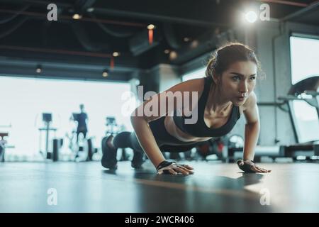 Sportliche Frau, die Liegestütze vom Boden aus im Fitnessstudio macht. Stockfoto